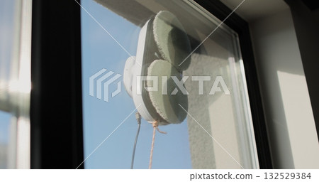 Close up automatic window cleaning robot operating on residential window. Simplicity and convenience of window cleaning. Close up automatic window cleaning robot operating on residential window. Simplicity and convenience of window cleaning. 132529384