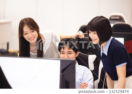 男男女女一邊看著電腦一邊交談。 132529874