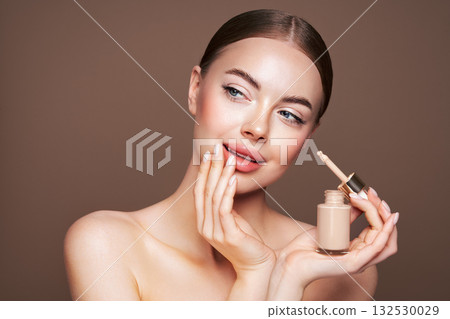 Portrait beautiful young woman with foundation bottle Portrait beautiful young woman with foundation bottle 132530029