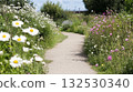 Path through the green meadow with blooming daisies and chamomiles under bright summer sky 132530340