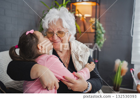 Grandma and granddaughter share a warm embrace indoors Grandma and granddaughter share a warm embrace indoors 132530393