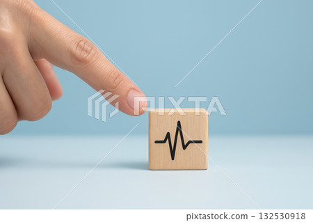 Wooden block with heartbeat symbol and finger pointing on blue background representing medical service and health insurance for wellness and care support 132530918