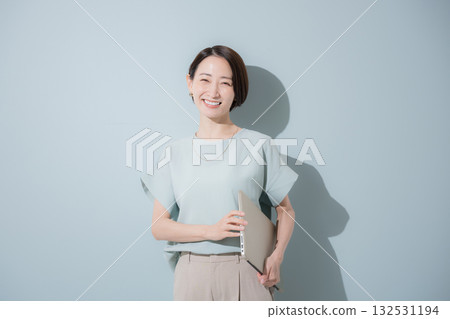 Image of a business woman with a beautiful mint green background holding a laptop Image of a business woman with a beautiful mint green background holding a laptop 132531194