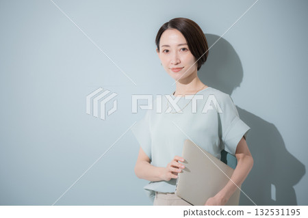 Image of a business woman with a beautiful mint green background holding a laptop Image of a business woman with a beautiful mint green background holding a laptop 132531195