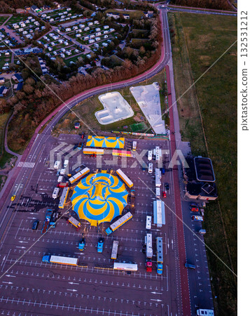 Aerial view of vibrant circus setup in parking lot blue yellow spiral tent surrounded by trailers and smaller tents, showcasing 132531212