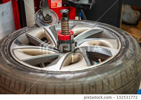 Tire changing machine removing the rubber tire from the rim using a rotating metal arm. Essential step in seasonal wheel replacement at a professional auto workshop. Tire changing machine removing the rubber tire from the rim using a rotating metal arm. Essential step in seasonal wheel replacement at a professional auto workshop. 132531772
