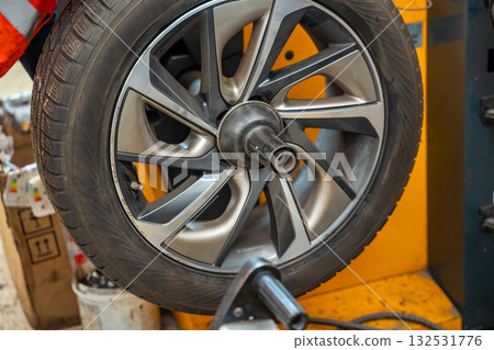 Car wheel rotating on a balancing machine during seasonal tire service at an auto workshop. Essential step to ensure smooth driving and tire longevity before winter installation. 132531776
