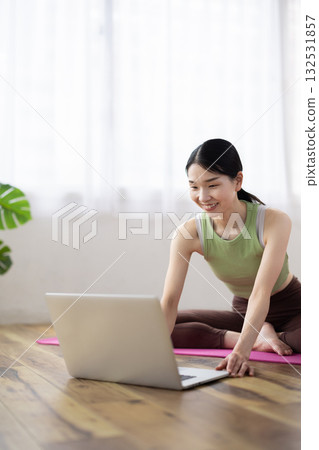 Middle-aged woman taking online yoga lessons using a laptop Middle-aged woman taking online yoga lessons using a laptop 132531857