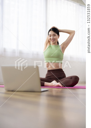 一位中年婦女正在使用筆記型電腦參加線上瑜珈課程。 132531859