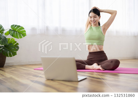 Middle-aged woman taking online yoga lessons using a laptop Middle-aged woman taking online yoga lessons using a laptop 132531860