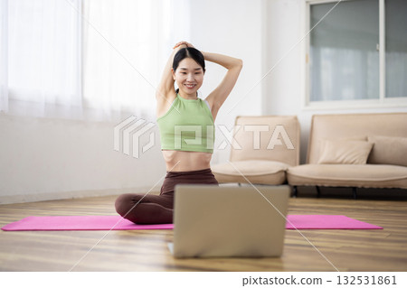 Middle-aged woman taking online yoga lessons using a laptop Middle-aged woman taking online yoga lessons using a laptop 132531861