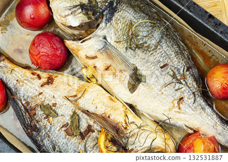 Baked dorado fish with plums served on a plate. 132531887