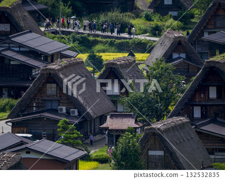 從空中俯瞰白川鄉的合掌造風格村落，可以看到歷史悠久的茅草屋頂房屋和來來往往的遊客。 132532835