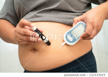 Asian woman injecting herself diabetes injecting insulin in stomach at home. 132533025
