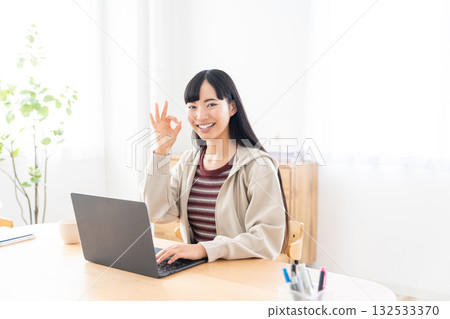 A female college student operating a computer at home 132533370