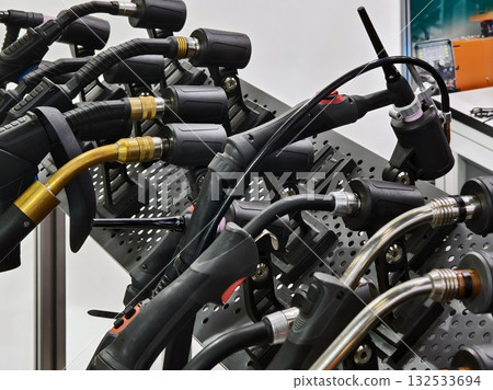 Welding torches and gas hoses displayed on a workbench at a technical exhibition in a workshop setting Welding torches and gas hoses displayed on a workbench at a technical exhibition in a workshop setting 132533694