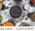 Collection of spices and herbs arranged in bowls with garlic and onion on a gray surface 132533695