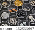 Variety of small metal and plastic parts organized in clear containers on a dark surface 132533697