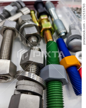 Various bolts and nuts arranged neatly on a work surface showcasing different colors and materials Various bolts and nuts arranged neatly on a work surface showcasing different colors and materials 132533703
