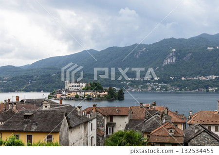 Lake Orta landscape with San Giulio Island, monastery, colorful houses and rustic rooftops reflected Lake Orta landscape with San Giulio Island, monastery, colorful houses and rustic rooftops reflected 132534455