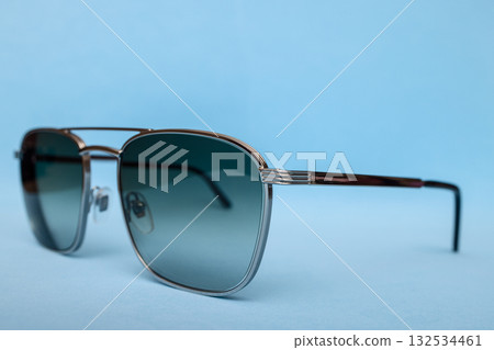 Clean elegant composition with metallic frame sunglasses and smoky gradient lenses on blue 132534461