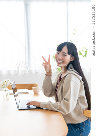 A female college student operating a computer at home A female college student operating a computer at home 132535196