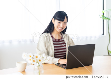 A female college student operating a computer at home 132535197