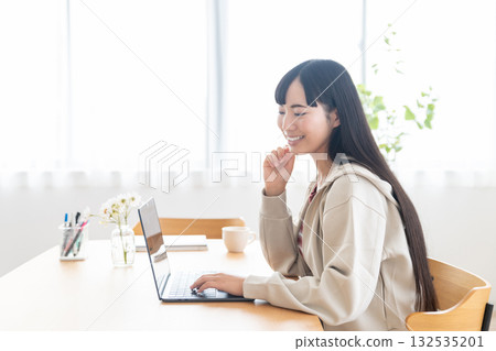 A female college student operating a computer at home 132535201