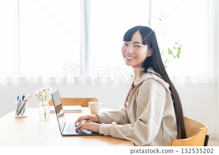 A female college student operating a computer at home 132535202