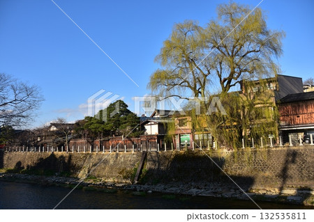 日本岐阜縣高山市-春季高山祭期間,熱門旅遊景點中橋周圍的街道,藍天白雲,古老的房屋和柳樹交相輝映。 日本岐阜縣高山市-春季高山祭期間,熱門旅遊景點中橋周圍的街道,藍天白雲,古老的房屋和柳樹交相輝映。 132535811