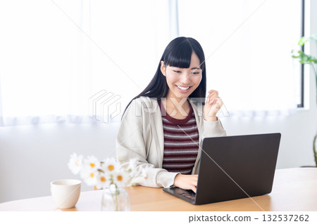 Young woman operating a personal computer at home Young woman operating a personal computer at home 132537262