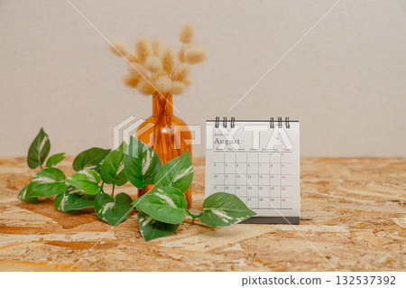 August 2026 desk calendar and dried flowers stock photo. There is a potted plant on an OSB plywood table. August 2026 desk calendar and dried flowers stock photo. There is a potted plant on an OSB plywood table. 132537392