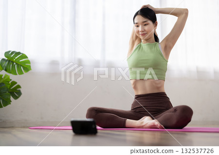 中年婦女一邊伸懶腰一邊看著她的智慧型手機 132537726