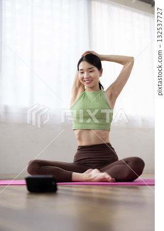 中年婦女一邊伸懶腰一邊看著她的智慧型手機 132537727