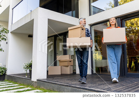 Senior male and female couple relocating carrying packed boxes 132537835