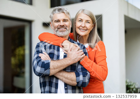 Cute woman in orange shirt hugging her husband and smiling nicely Cute woman in orange shirt hugging her husband and smiling nicely 132537959