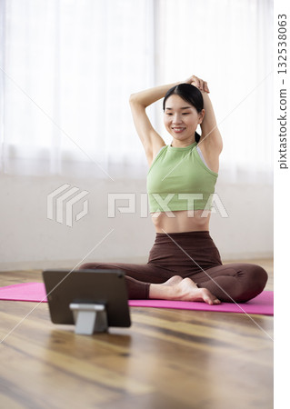 Middle-aged woman stretching while looking at a tablet 132538063
