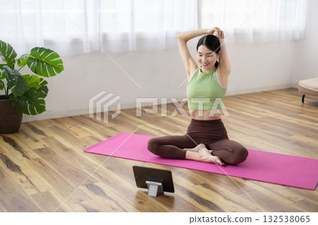 Middle-aged woman stretching while looking at a tablet Middle-aged woman stretching while looking at a tablet 132538065