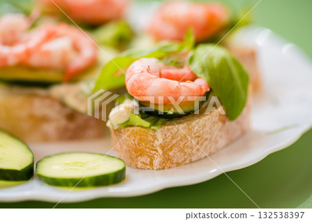 Isolated mini canapes with shrimps, lettuce and cucumber, on a green background Isolated mini canapes with shrimps, lettuce and cucumber, on a green background 132538397