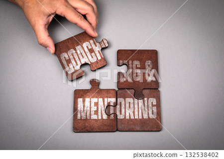 Coaching and Mentoring Concept. Wooden puzzle pieces with text on a gray background Coaching and Mentoring Concept. Wooden puzzle pieces with text on a gray background 132538402