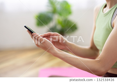 一位身穿瑜珈服的女性正在操作智慧型手機。 132538416