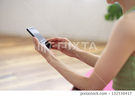 一位身穿瑜珈服的女性正在操作智慧型手機。 132538417