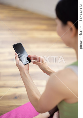 The hands of a woman wearing yoga wear and operating a smartphone The hands of a woman wearing yoga wear and operating a smartphone 132538418