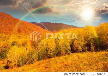landscape with autumn forest at sunset. nature park with birch trees in colorful foliage in evening light. clouds on sky above mountains. horizontal travel background under rainbow landscape with autumn forest at sunset. nature park with birch trees in colorful foliage in evening light. clouds on sky above mountains. horizontal travel background under rainbow 132538654