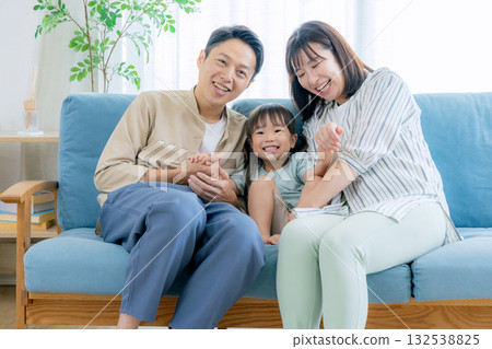 Couple and child sitting on sofa 132538825