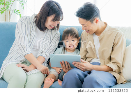 family looking at tablet in living room family looking at tablet in living room 132538853