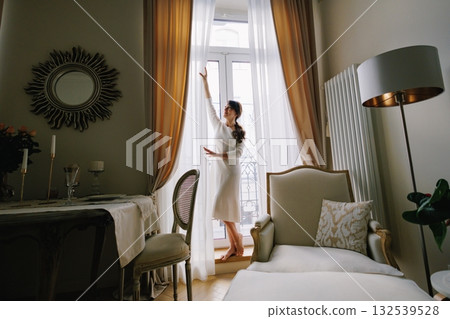 Woman opening curtains in morning light Woman opening curtains in morning light 132539528