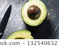Fresh avocado halves on dark stone background 132540632