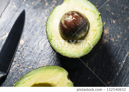 Fresh avocado halves on dark stone background Fresh avocado halves on dark stone background 132540632