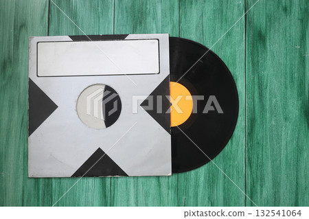 Aged black paper cover and vinyl LP record isolated on green background 132541064